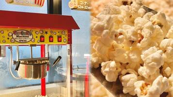 Una máquina de palomitas de maíz con un recipiente grande lleno de palomitas y una cuchara para servir.