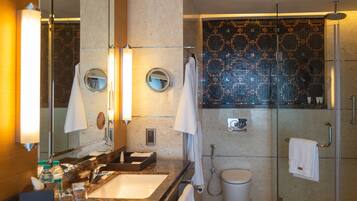 A modern bathroom with a glass shower enclosure, a marble sink, and a large mirror.