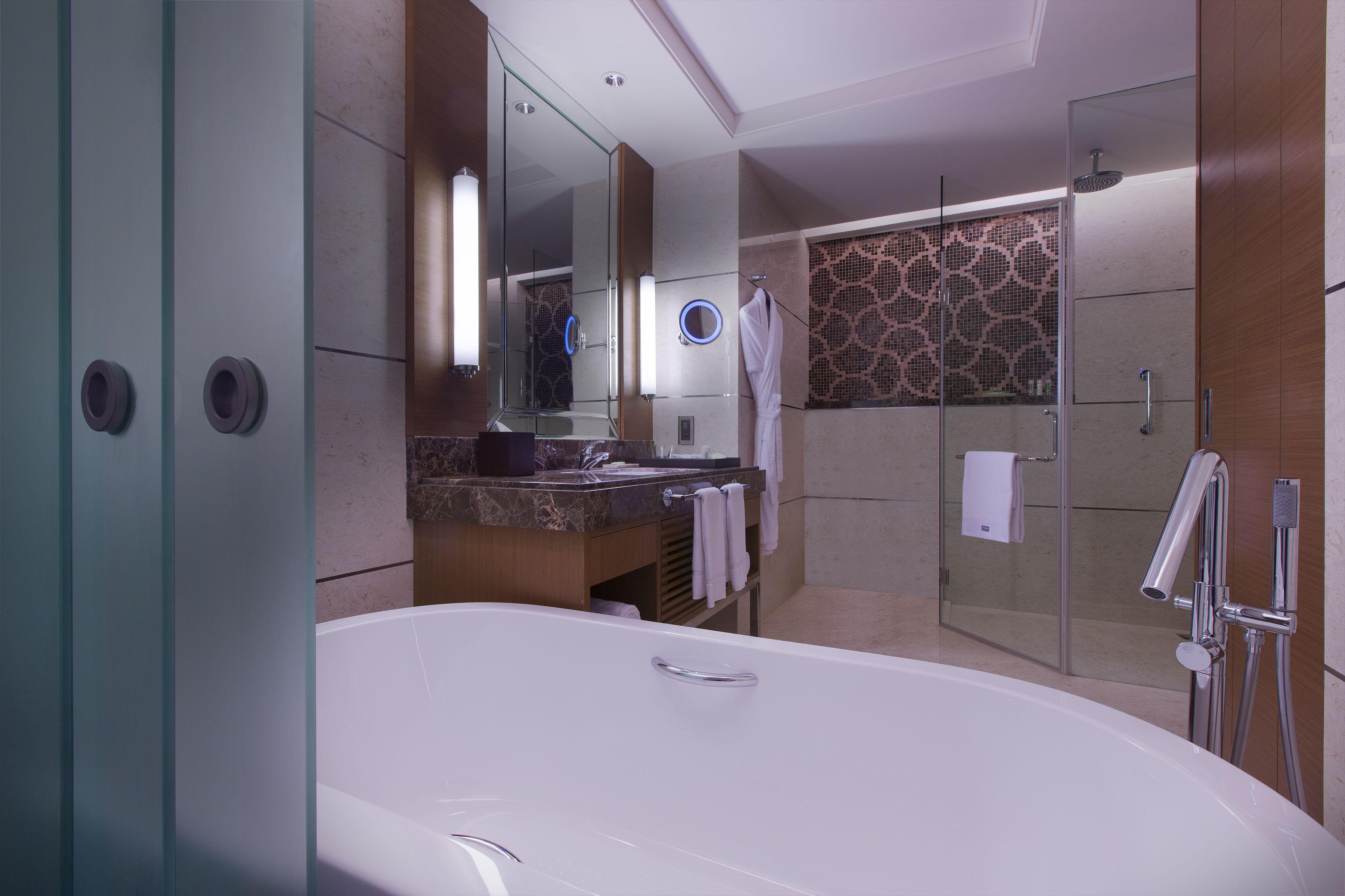 A modern bathroom with a large bathtub, a glass-enclosed shower, and a vanity with a mirror.