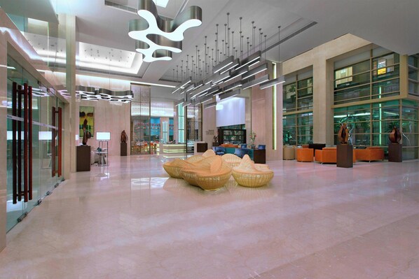 A spacious lobby with modern furniture, a reception desk, and large windows.