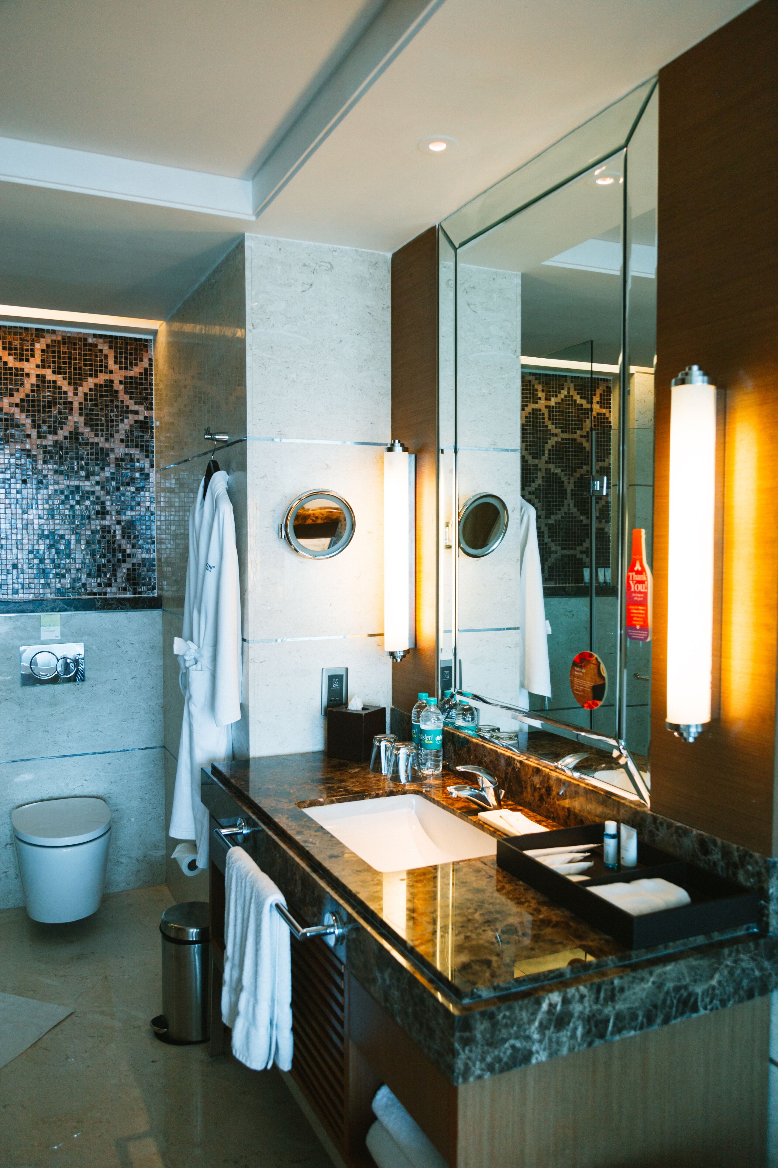 A modern bathroom with a marble sink, a large mirror, and a glass shower enclosure.