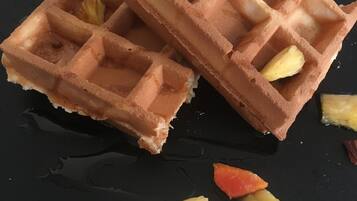 Two waffles with fruit and whipped cream on a black plate.