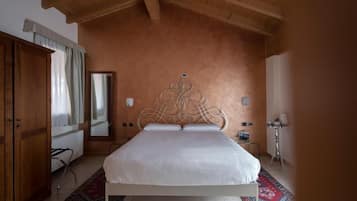 Un dormitorio con cama blanca, armario de madera y un espejo grande.