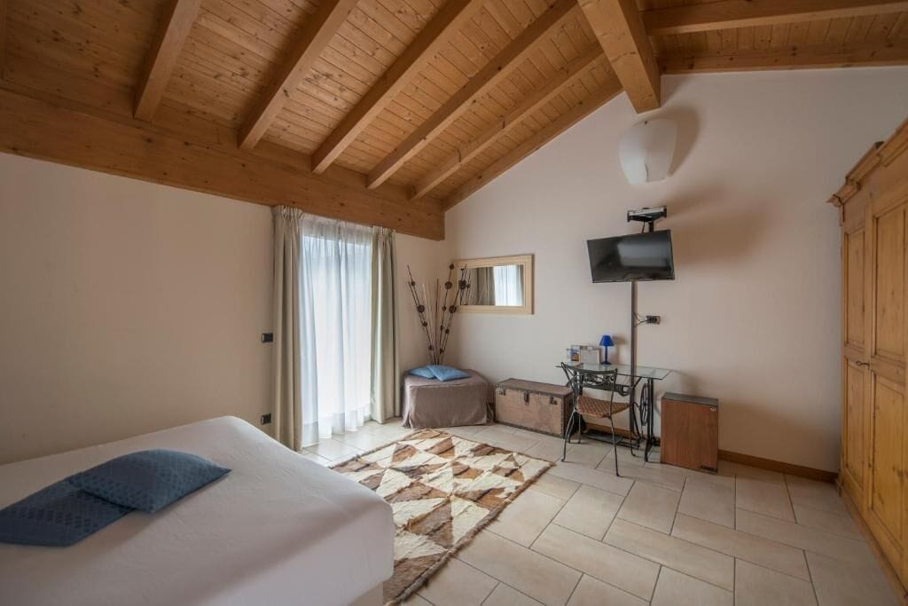 Un dormitori amb llit, escriptori, televisió i armari.
