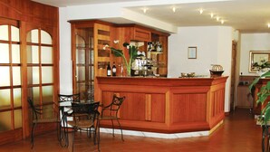 A bar area with wooden cabinetry, a glass display case, and a seating arrangement with chairs. - Hotel Villa Colico (Colico)