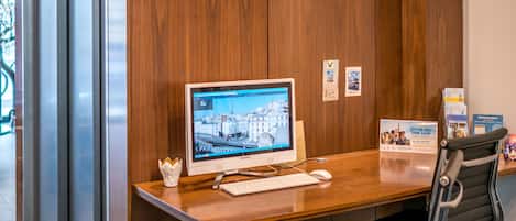A modern office space with a wooden panel wall, a desktop computer, a keyboard, a mouse, and a black office chair.