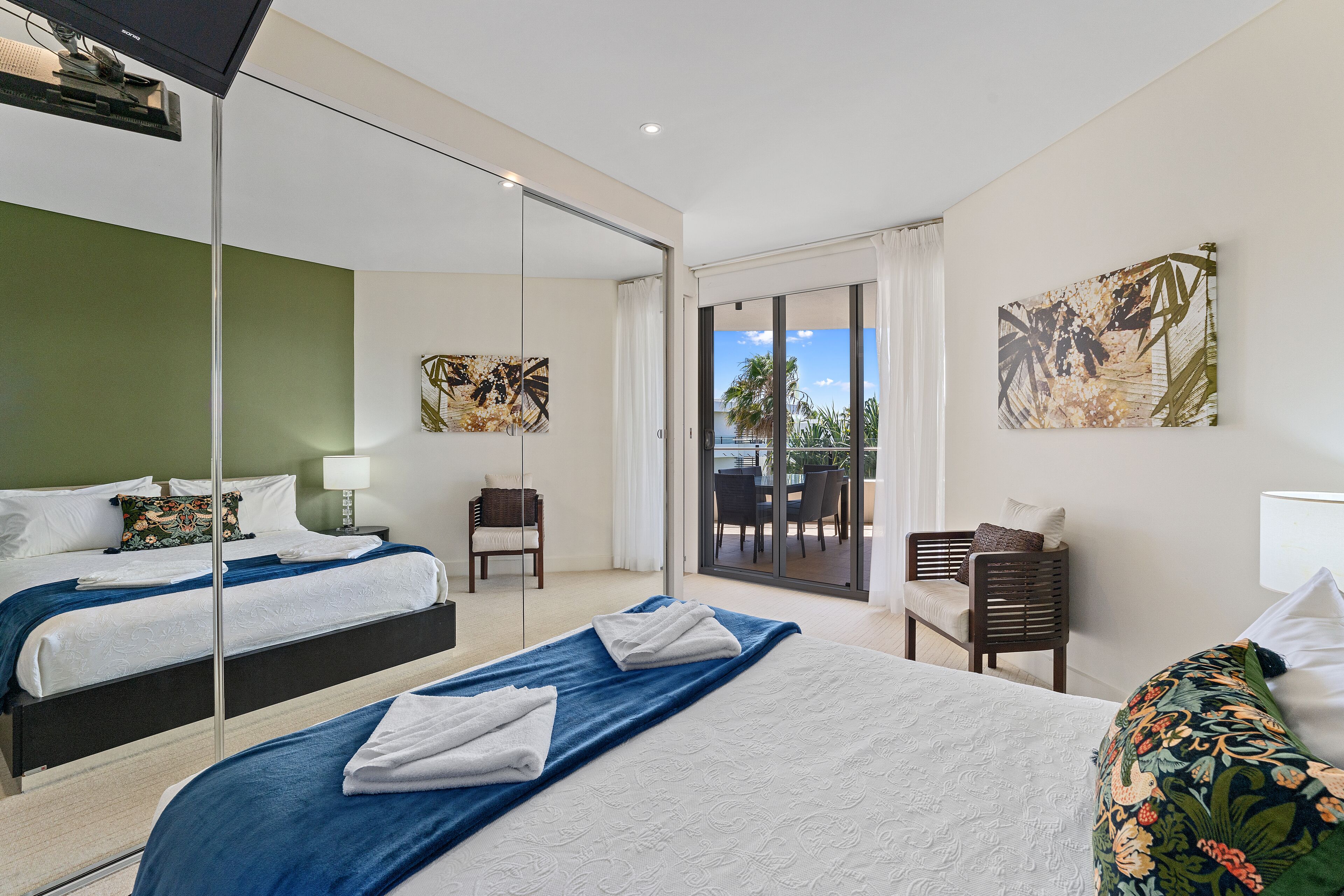 Ein Hotelzimmer mit zwei Betten, einem Balkon mit Blick und Kunstwerken an den Wänden.
