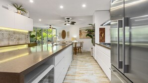 Una cocina moderna con una isla grande, electrodomésticos de acero inoxidable y un ventilador de techo.
