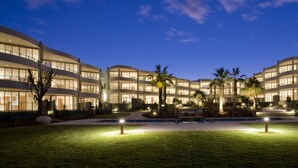 Un hotel moderno con varios pisos, un patio central y zonas exteriores bien iluminadas.