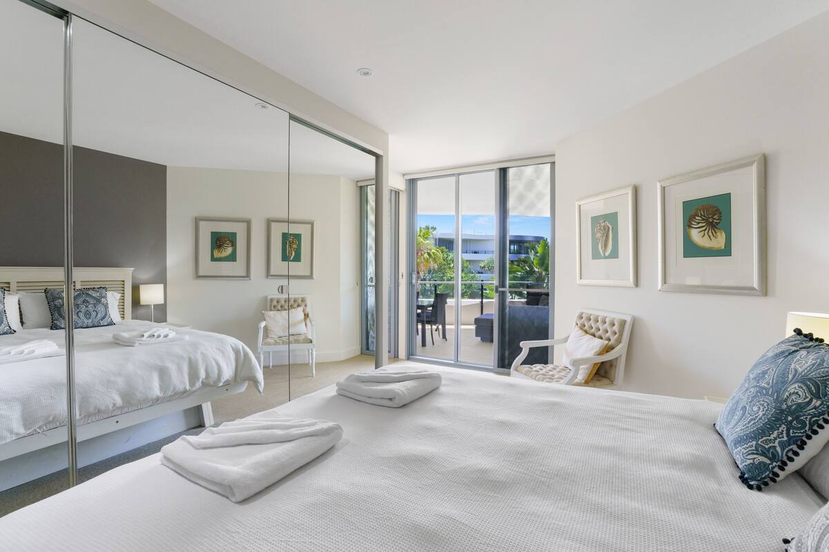 Een moderne hotelkamer met twee bedden, een balkon en uitzicht, en kunstwerken aan de muren.