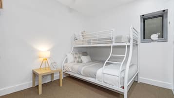 Cozy bedroom with a bunk bed setup, bedside table, and a window offering a view of the outside.