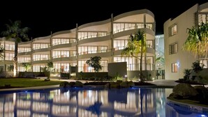 Un hotel moderno con una piscina grande, varios balcones e interiores bien iluminados.