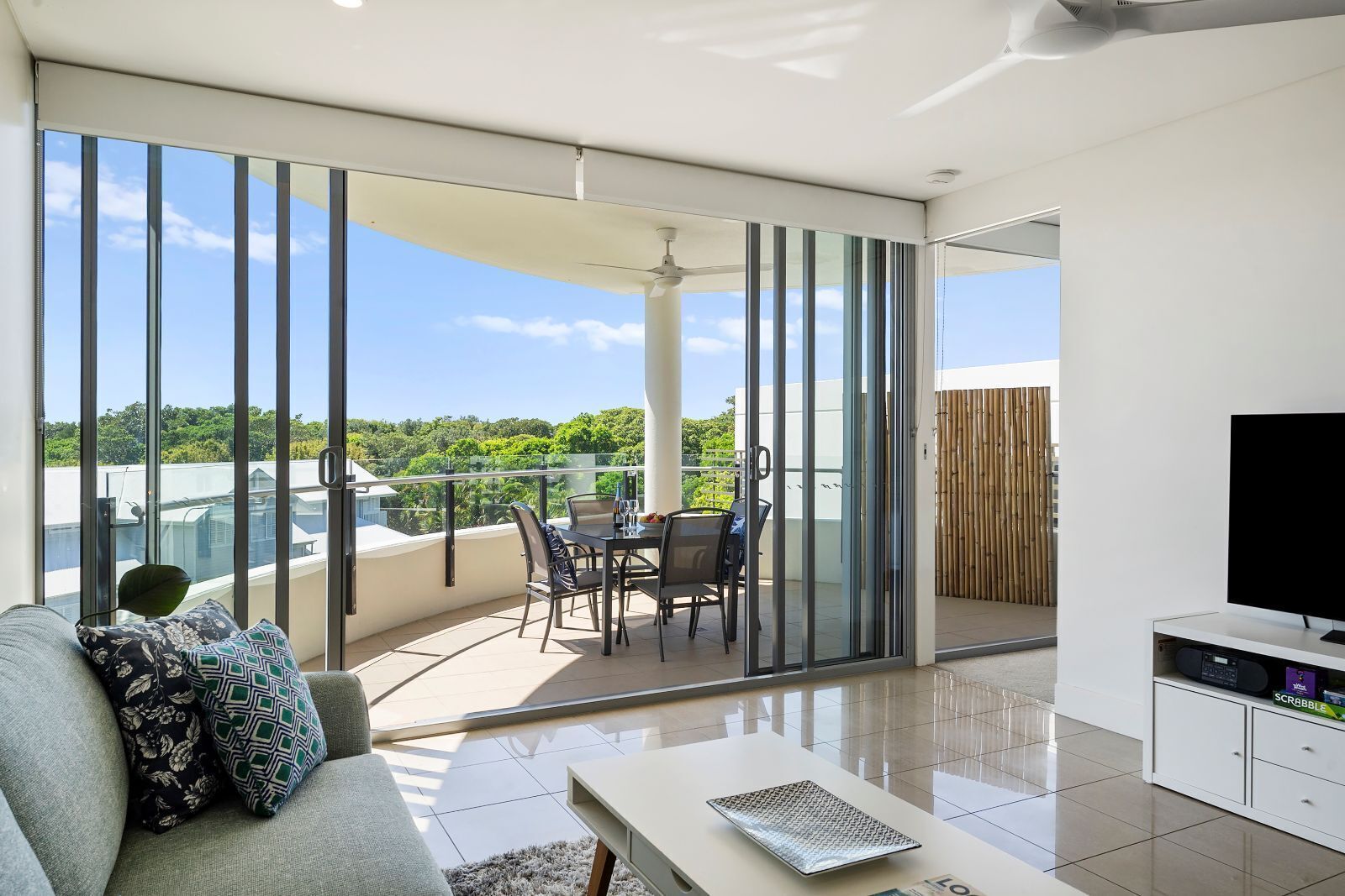 A modern living room with a balcony, a sofa, a coffee table, and a TV.