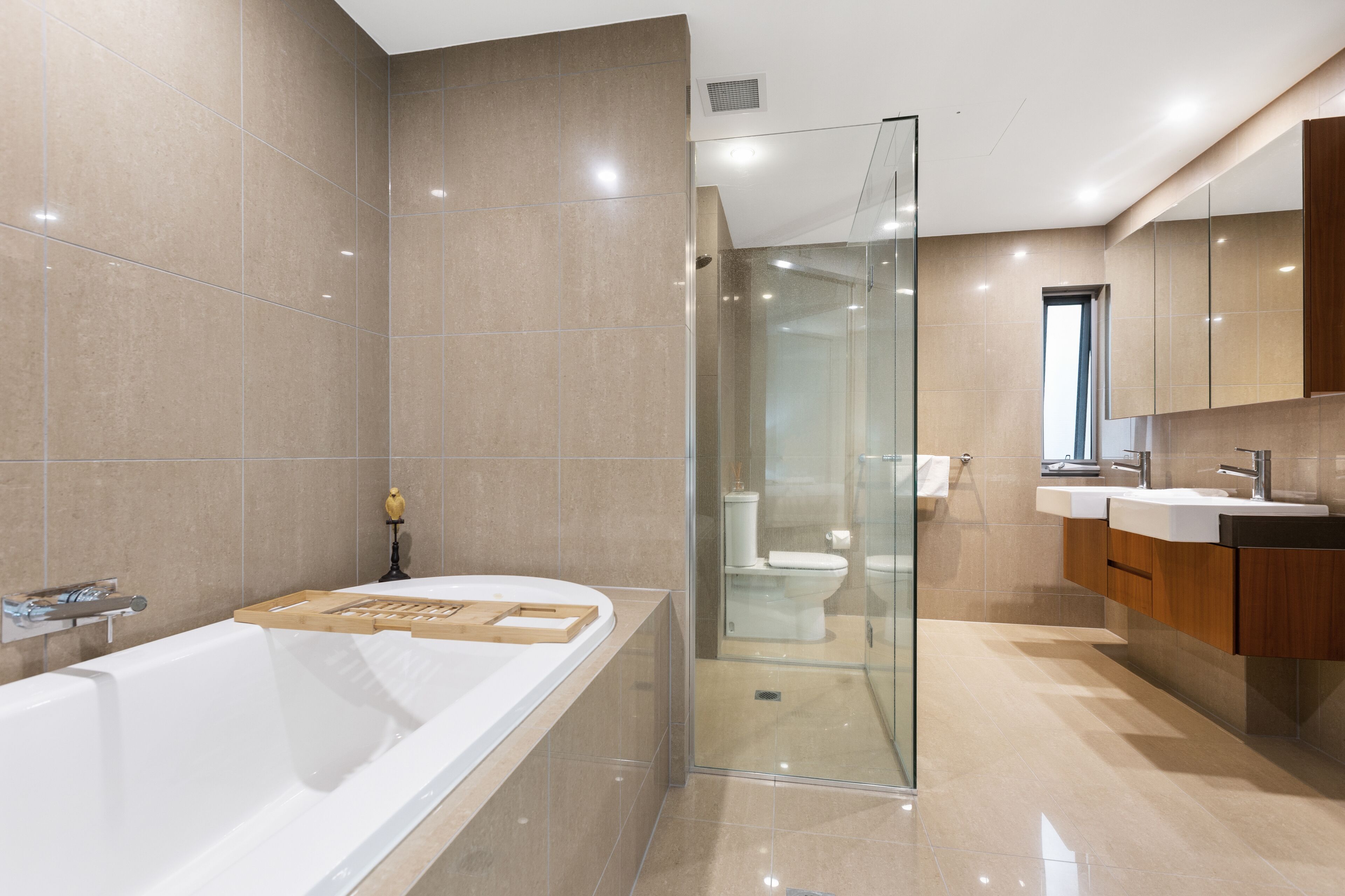 A modern bathroom with a large bathtub, a glass-enclosed shower, and wooden bath mats.
