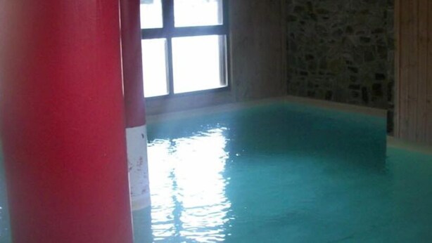 An indoor swimming pool with a stone wall and a window. - Les Hauts Plateaux (Ax-les-Thermes)