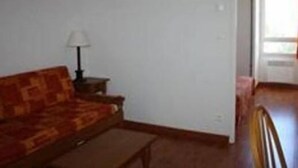A living room with a sofa, a lamp, and a small table. - Les Hauts Plateaux (Ax-les-Thermes)