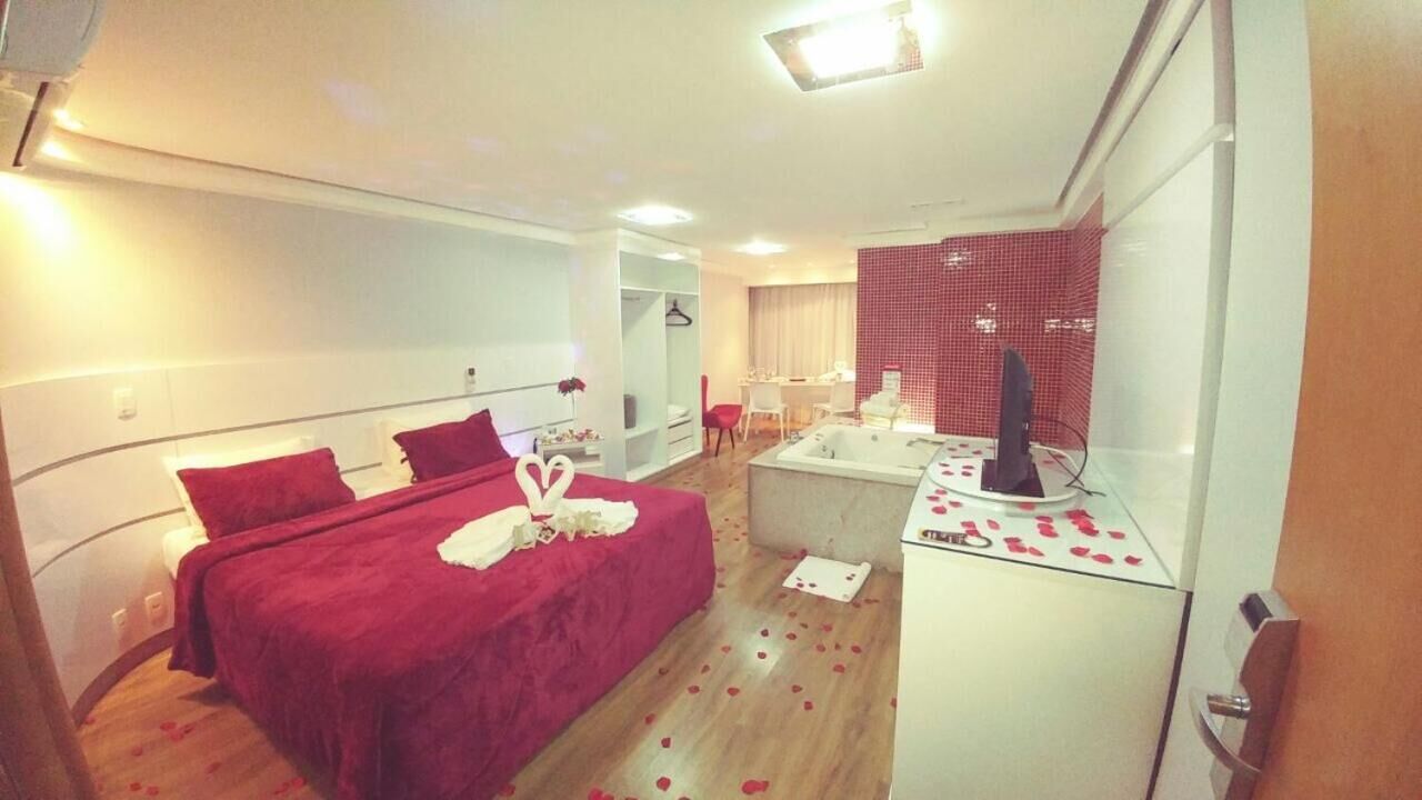A hotel room with a bed, a desk with a computer, a bathroom, and a shower area.