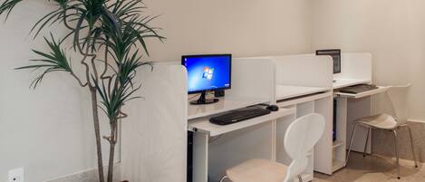 Un espacio de oficina moderno con cubículos, un monitor de computadora, teclado y una planta en maceta.