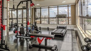 A gym with weightlifting equipment, a bench, and dumbbells. - Brisa Tower Hotel (Ceilandia)