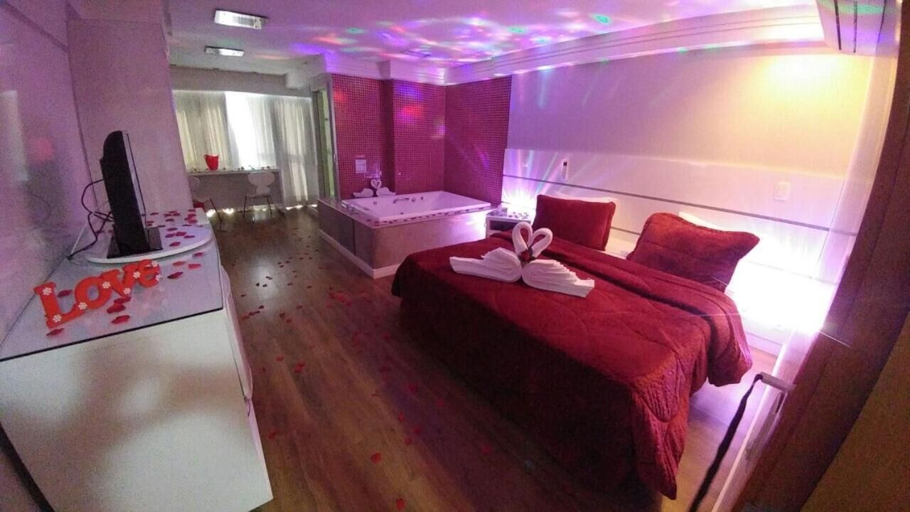 Ein Hotelzimmer mit roter Bettdecke, einem großen Fenster und einer Whirlwanne.