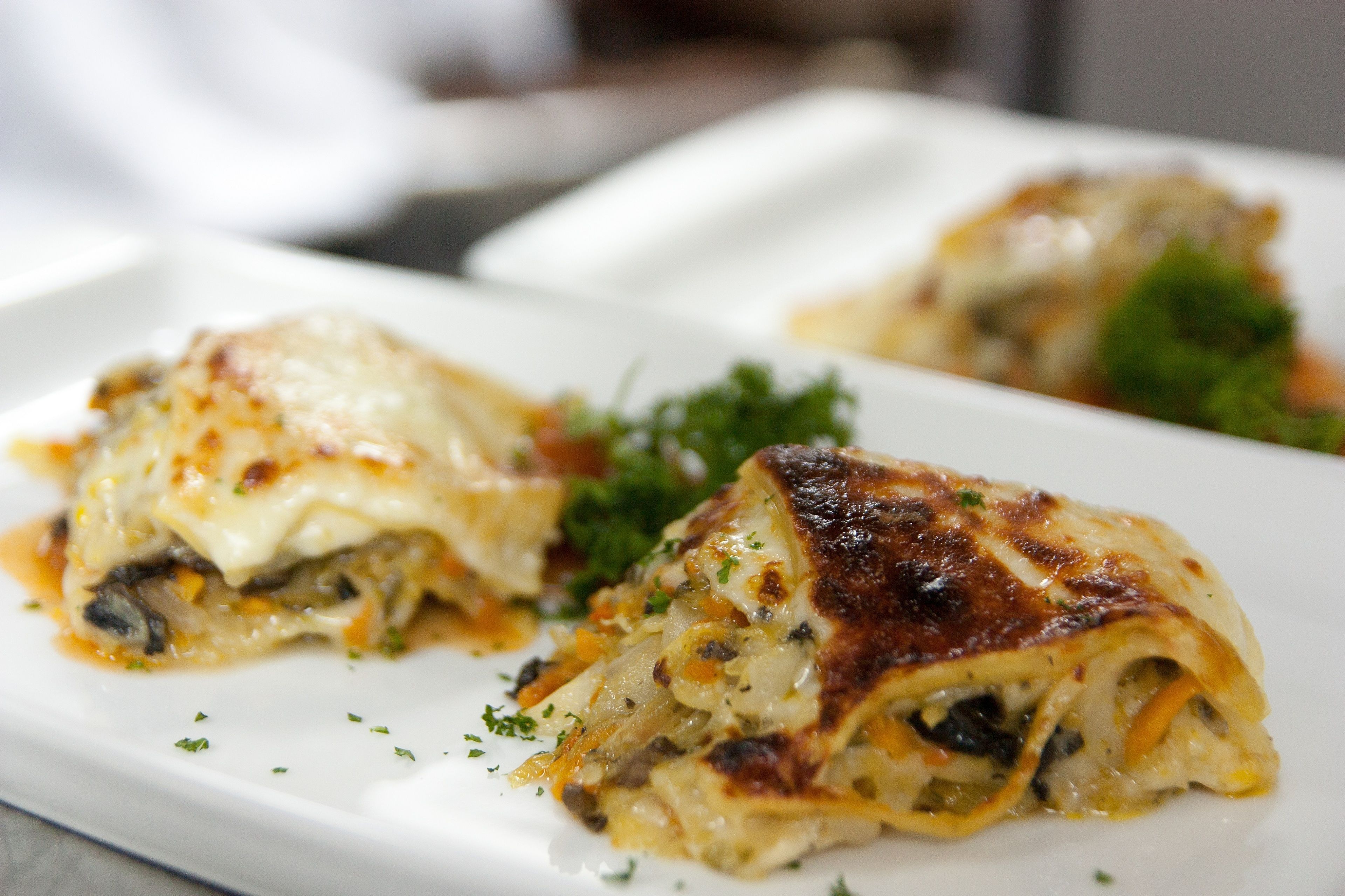 A plate of lasagna with melted cheese and herbs.
