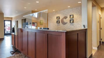 A reception desk with a stone wall backdrop, a wooden counter, and a glass partition.