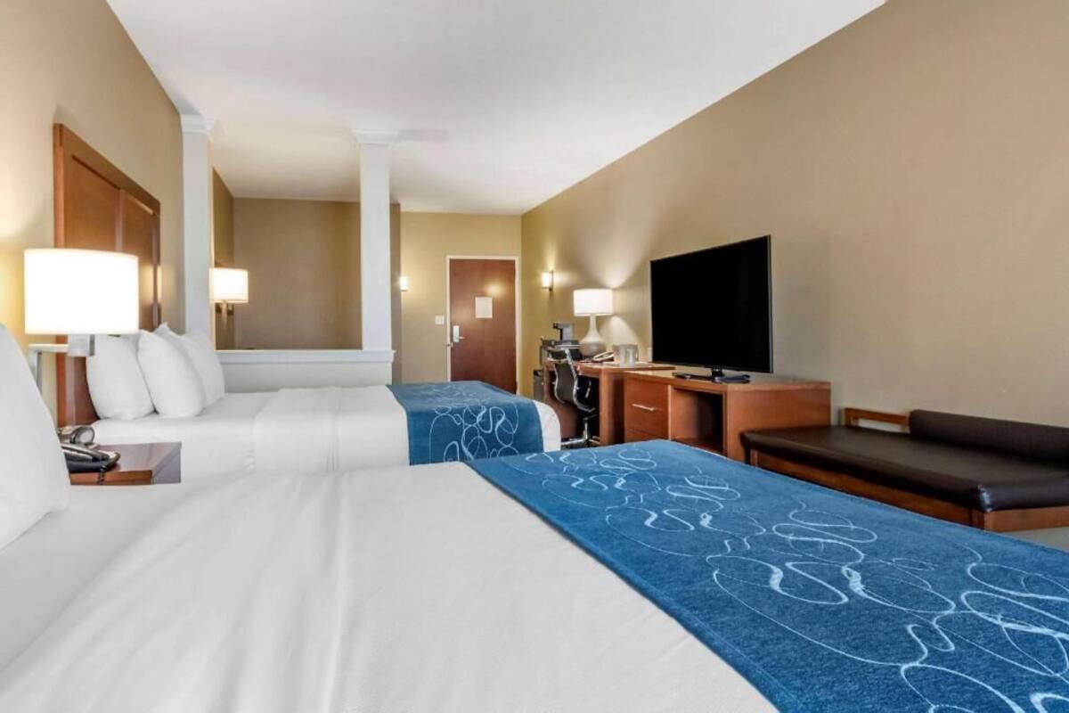 A hotel room with two beds, a desk, a TV, and a sofa.