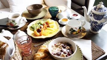 A breakfast setting with a variety of food items, including fruits, a croissant, and a bowl of cereal.