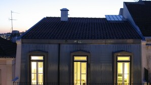 Un edificio de dos pisos con un balcón en el segundo nivel, una puerta visible y paredes exteriores con diseño.