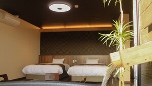 Habitación de hotel con bañera de hidromasaje, dos camas y un atril de madera para plantas.