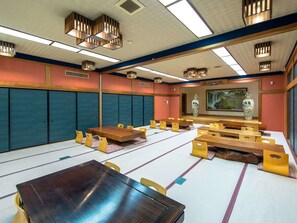 A traditional tatami mat room with wooden tables and benches, a large painting on the wall, and a ceiling with recessed lighting. - LiVEMAX RESORT Kinugawa (Nikko)