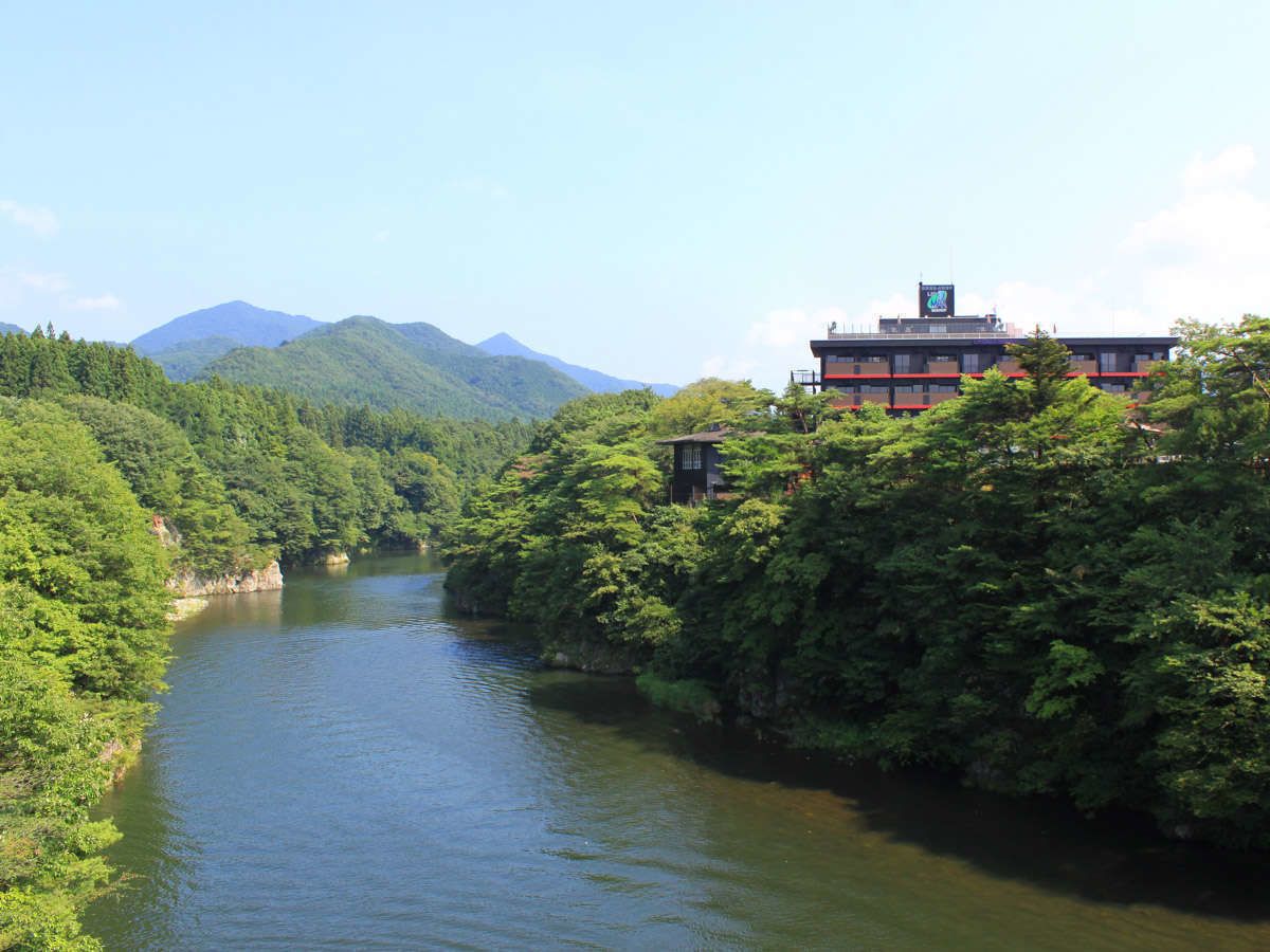Un río flanqueado por abundante vegetación y un edificio de varios pisos con techo rojo.