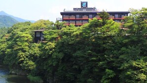 Un edificio de varios pisos rodeado de abundante vegetación y una masa de agua.