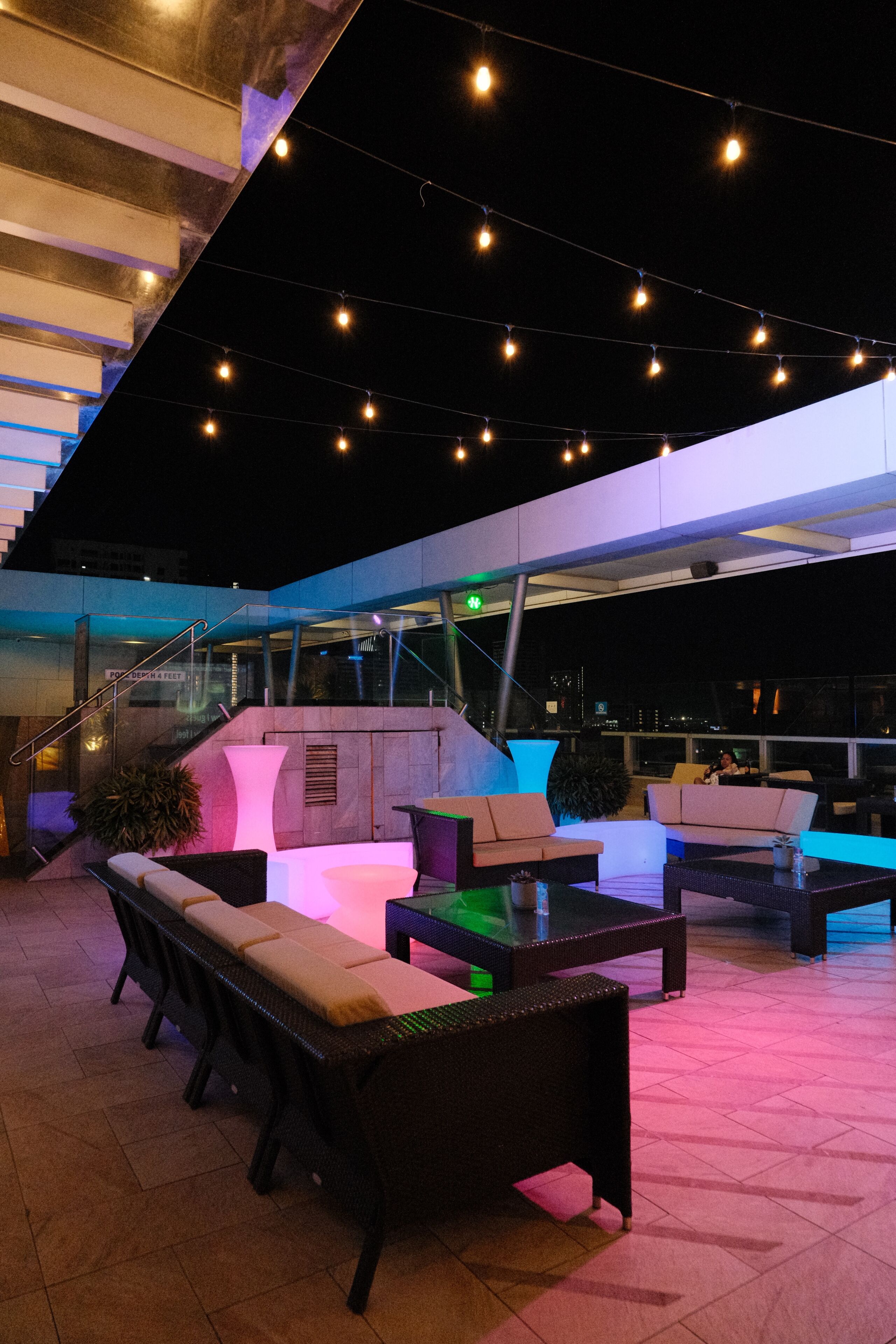 An outdoor seating area with modern furniture and string lights.