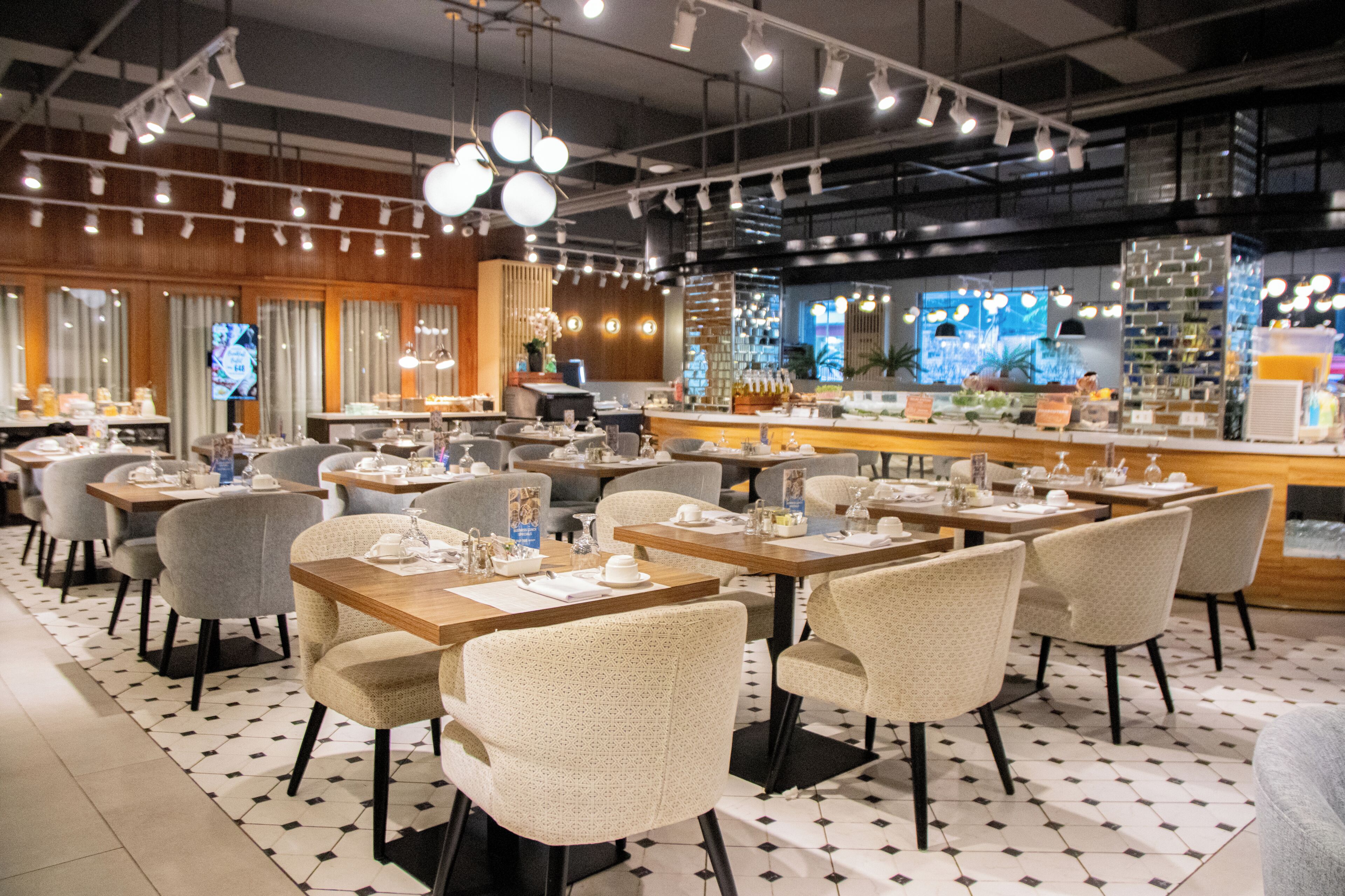 A restaurant with multiple tables and chairs, a bar area, and a television screen.