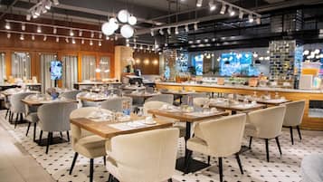 Un restaurant doté de plusieurs tables et chaises, d’un bar et d’un écran de télévision.