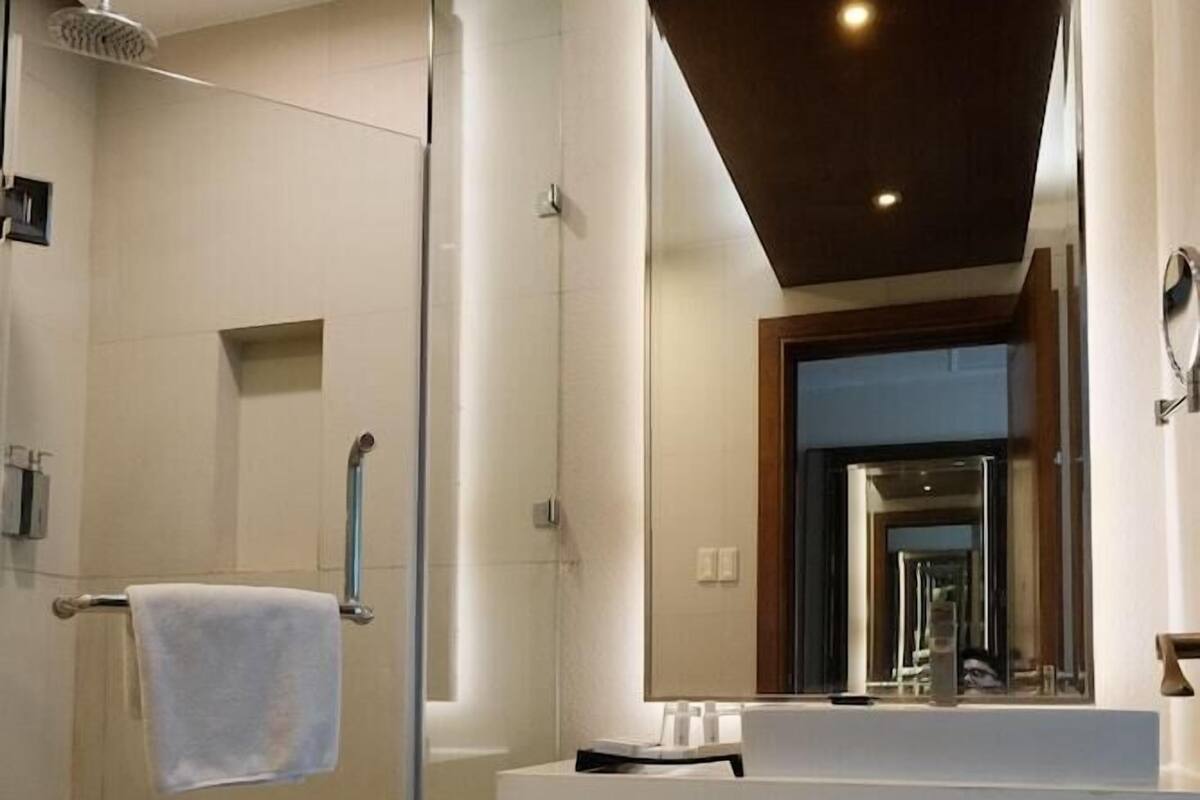 A modern bathroom with a glass shower enclosure, a white vanity with a mirror, and a recessed ceiling light.