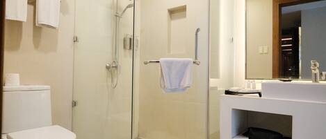 A modern bathroom with a glass-enclosed shower, a white toilet, and a vanity with a mirror.