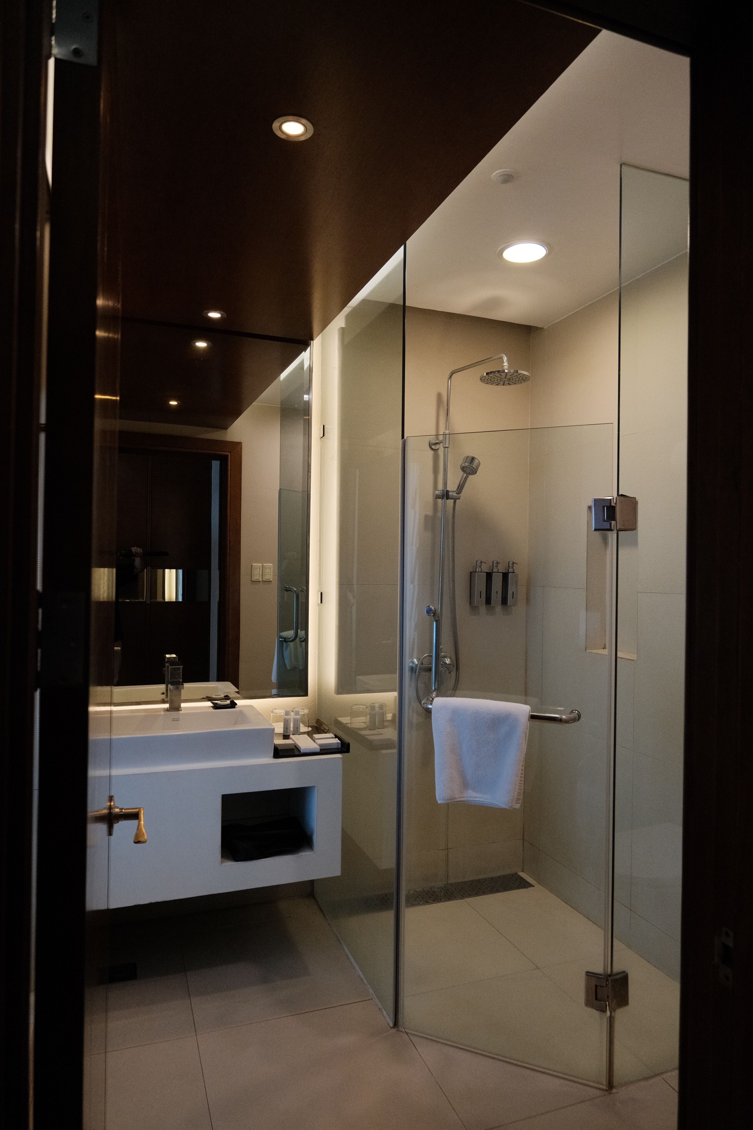 A modern bathroom with a glass-enclosed shower, a white vanity with a sink, and a mirror.