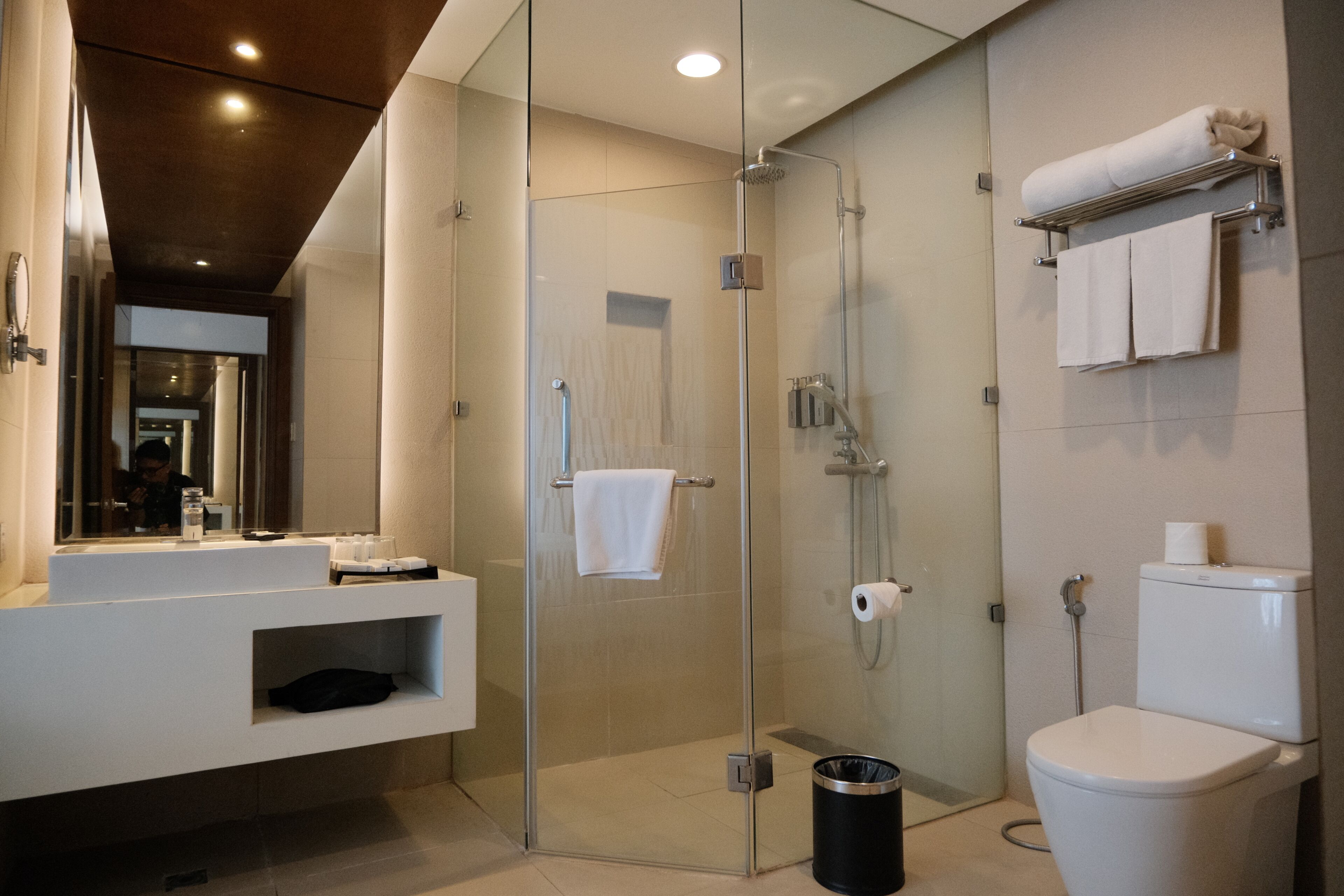 A modern bathroom with a glass-enclosed shower, a white toilet, and a vanity with a mirror.