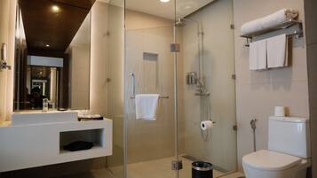 Un baño moderno con ducha de vidrio, inodoro blanco y tocador con espejo.