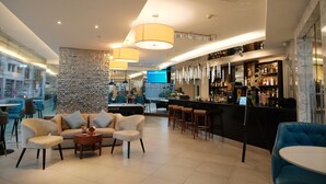 Un área de bar moderna con pared de piedra, sofás y mesa de billar.