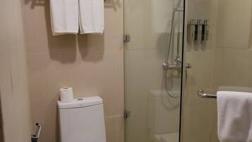 Ein Badezimmer mit Toilette, einer Duschkabine, einem Handtuchhalter und einem Mülleimer.
