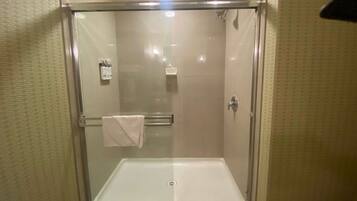 A glass-enclosed shower with a white bathtub, a towel rack, and a showerhead.