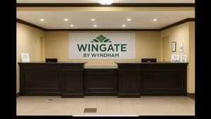 A reception desk with a banner reading "Wingate by Wyndham" and a sign indicating "The Wingate Experience".