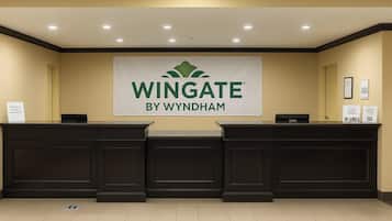 A reception desk with a banner reading "Wingate by Wyndham" and a sign indicating "The Wingate Experience".