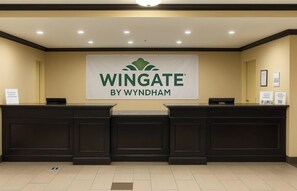 A reception desk with a banner reading "Wingate by Wyndham" and a sign indicating "The Wingate Experience". - Wingate by Wyndham Fort Saskatchewan (Fort Saskatchewan)