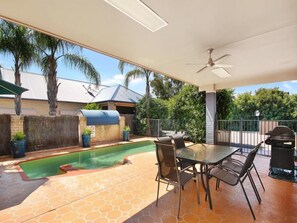 A covered outdoor area with a pool, a table with chairs, and a barbecue grill. - Edward Parry Motel & Apartments (South Tamworth)