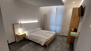 Un dormitorio moderno con cama, mesita de noche y un pequeño banco de madera.