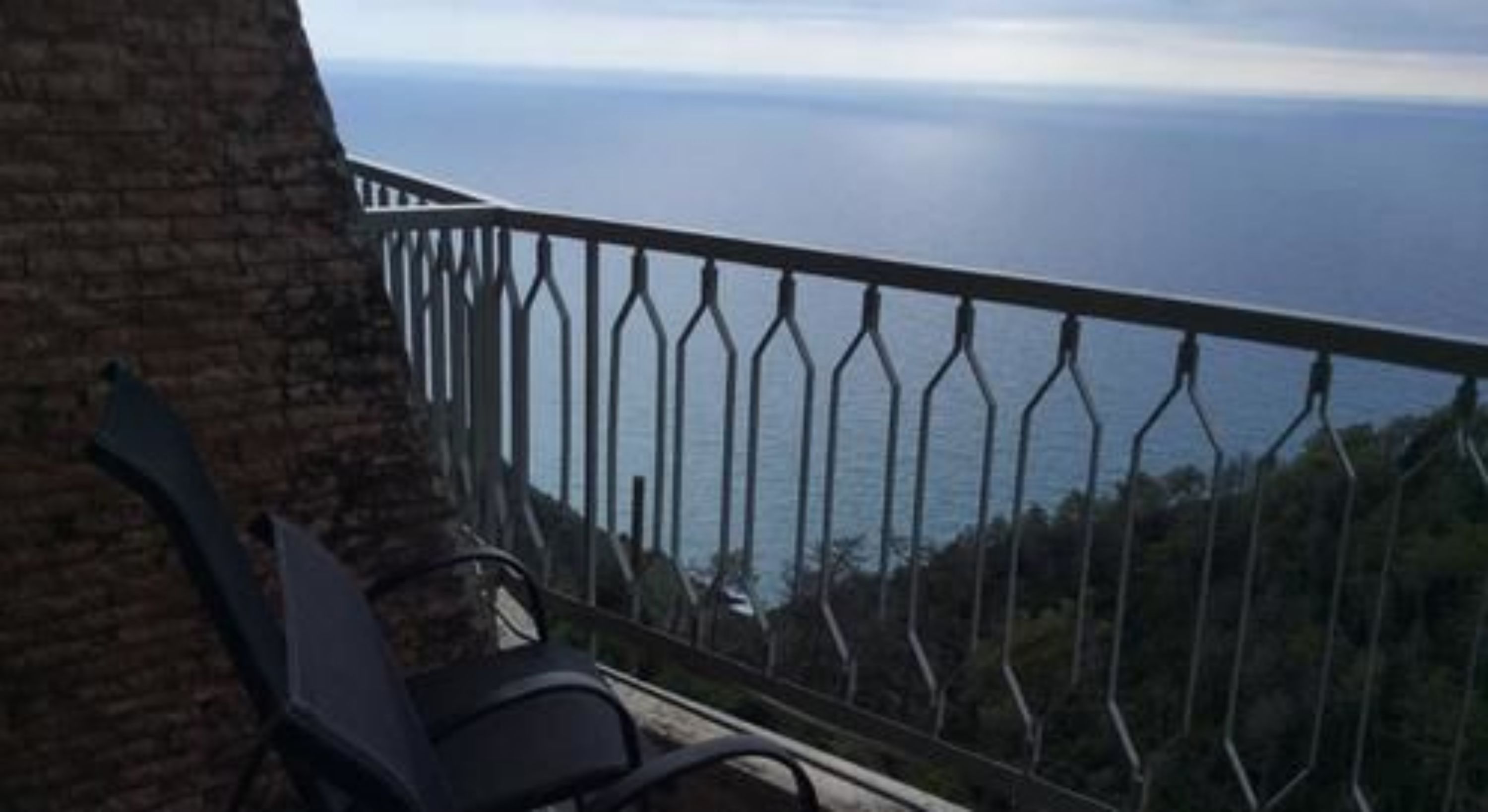 A balcony with a metal railing overlooking a coastal view.